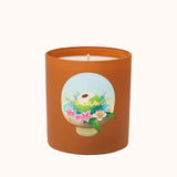 Candle in an orange container with a decorative label on a white background