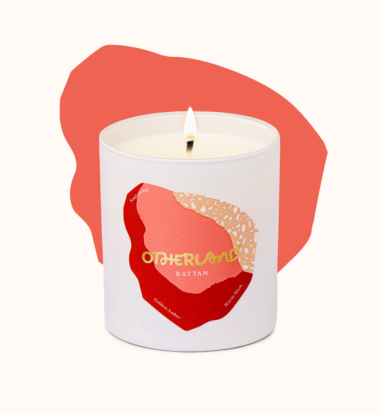 Rattan candle in a white container with a red and gold design, labeled 'Otherland' on a white background.