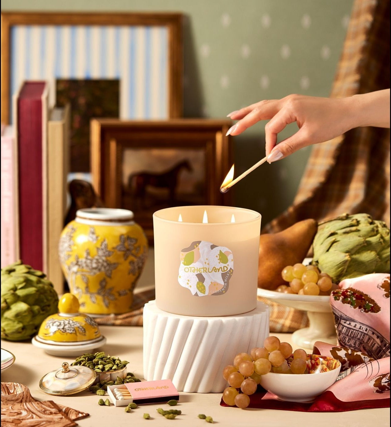 Hand lighting a candle with decorative items around