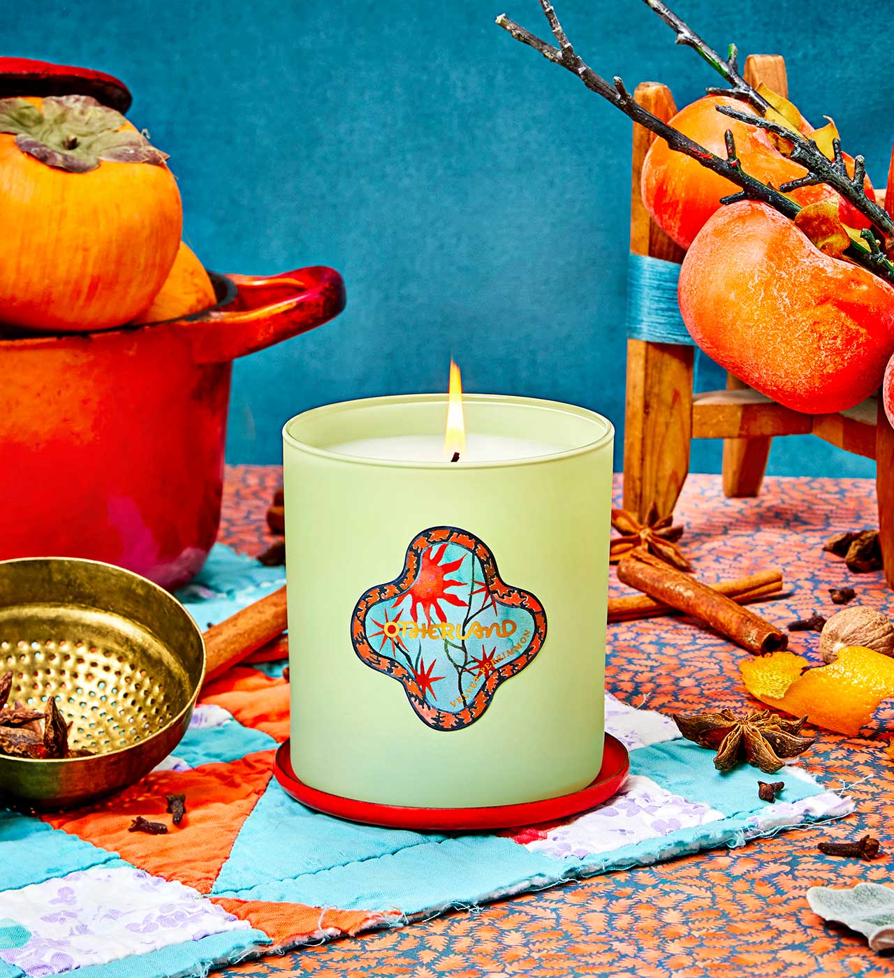 Candle with decorative label on a colorful tablecloth with pumpkins and cinnamon sticks.